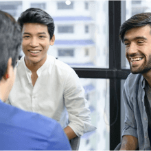 Three men sitting in a circle together laughing